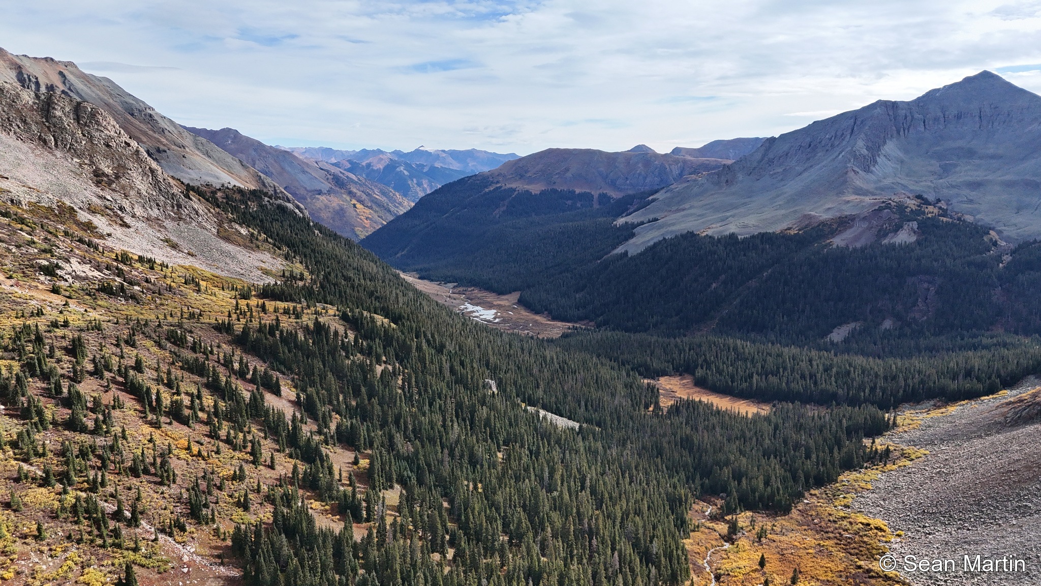 Broad mountain valley with evergreen forest and fall color
