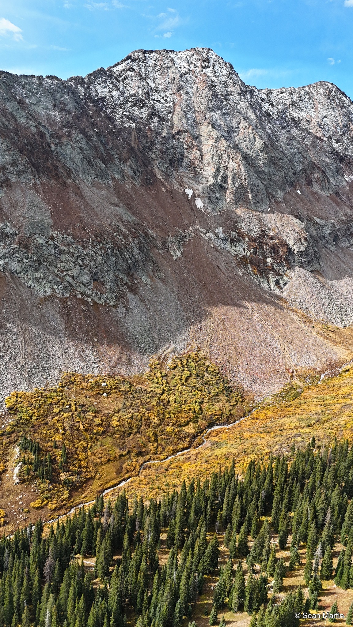 Rocky mountain face above autumn aspens
